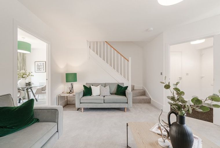 A living room with a sofa, staircase, and an adjacent dining area.