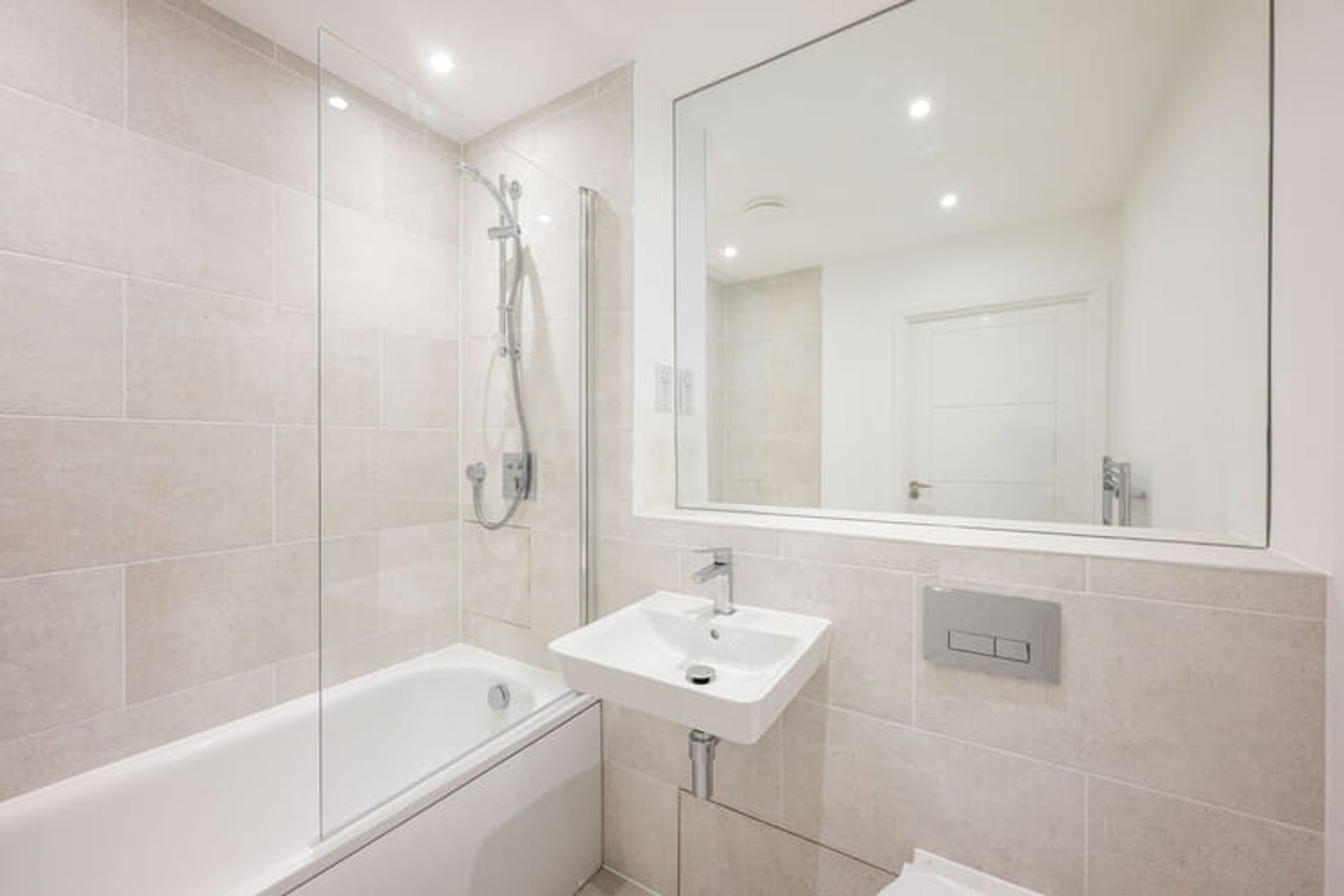 A bathroom with a bathtub, shower, sink, and mirror.