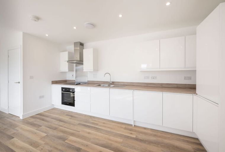 A modern kitchen with white cabinets, a built-in oven, and a sink.