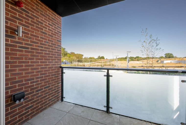 A balcony with a brick wall and a glass railing overlooking a construction site.