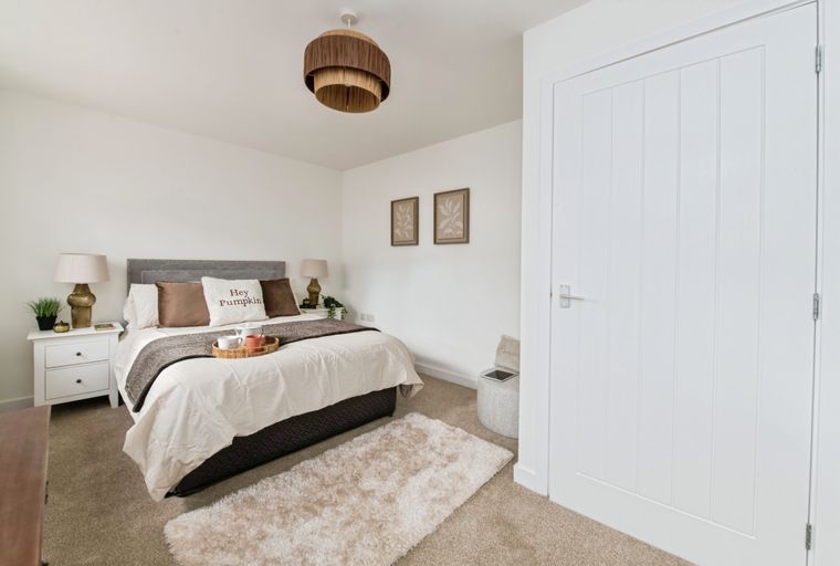 A bedroom with a bed, bedside table, rug, and a white door.