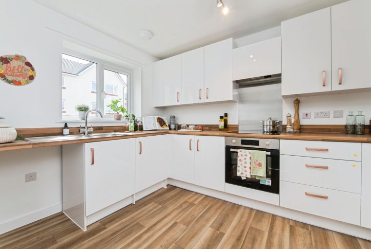 A modern kitchen with white cabinets, wooden countertops, and a sink.
