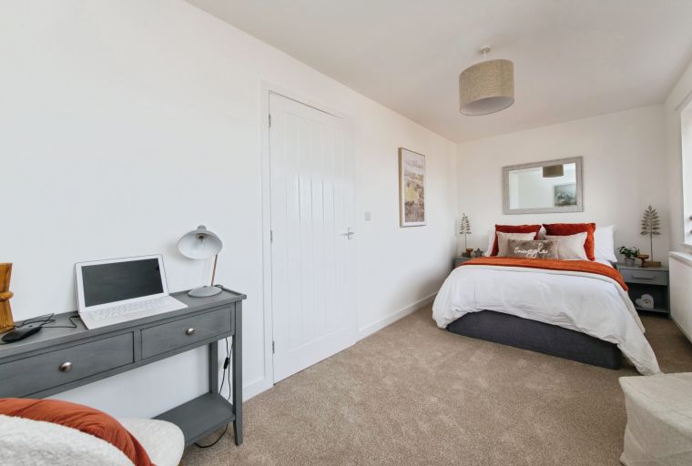 A bedroom with a bed, a desk, and a door.