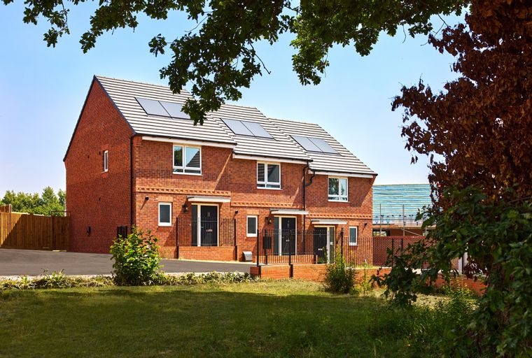 A row of new brick townhouses with solar panels on the roof.