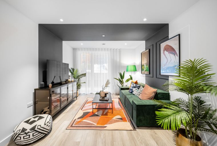 A living room with a green sofa, coffee table, and abstract rug.