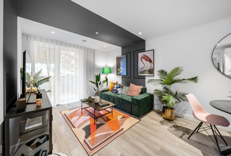 A living room with a green sofa, coffee table, and abstract art.