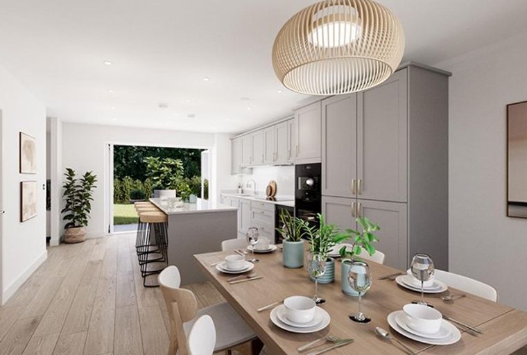 A modern kitchen and dining area with a large island and bi-fold doors opening to a garden.