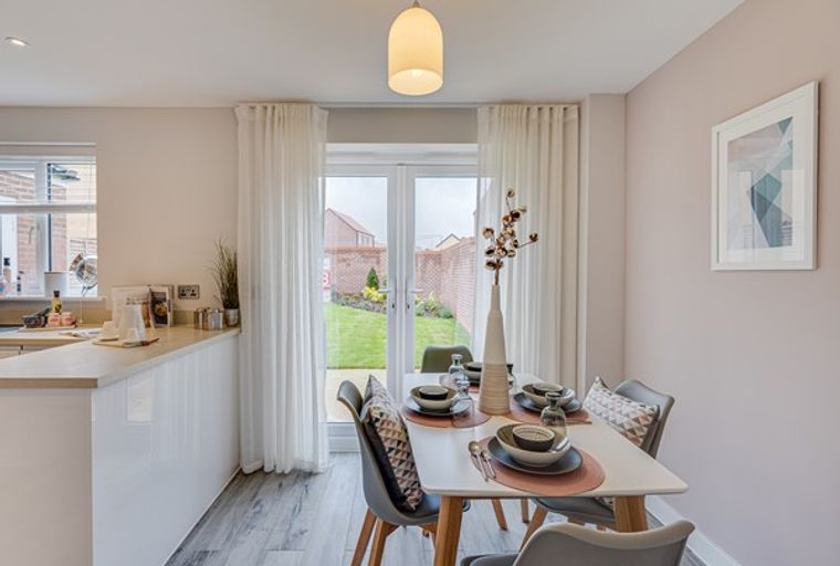 A dining area with a table and chairs set up in front of a glass door leading to a backyard.
