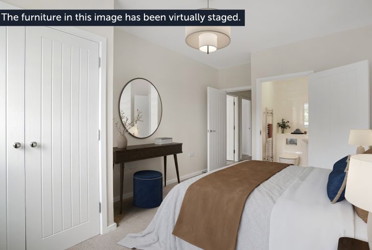 A bedroom with a bed, a console table, a mirror, an ottoman, and an en-suite bathroom.