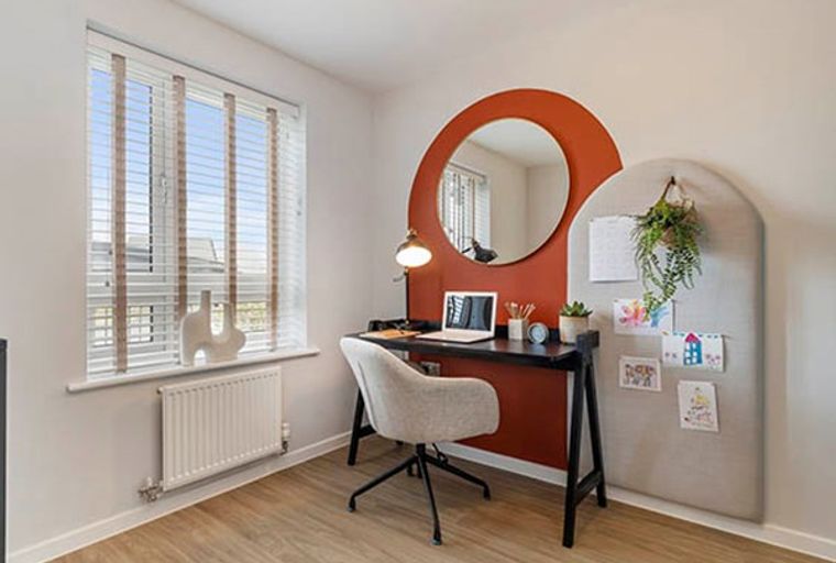 A home office with a desk, chair, mirror, and pinboard.