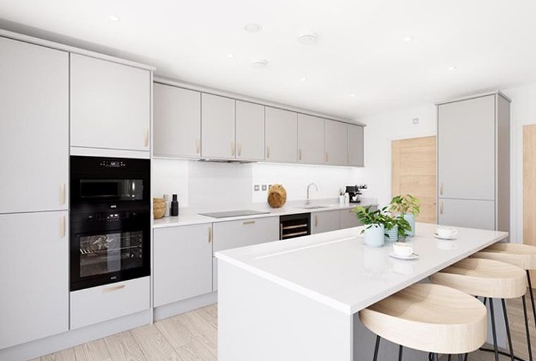 A modern kitchen with light grey cabinets, integrated ovens, and a large island with bar stools.