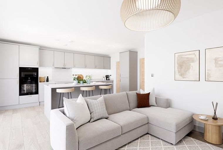 A modern living room and kitchen area with a sectional sofa, kitchen island with bar stools, and contemporary light fixtures.