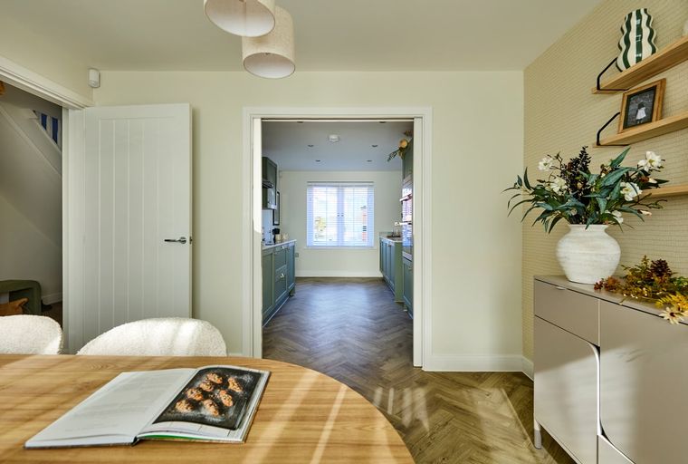 A dining area and kitchen with green cabinets and a herringbone floor.