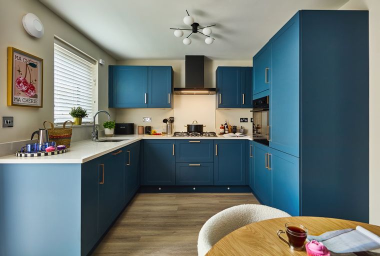 A modern kitchen with blue cabinets, white countertops, and a gas stove.