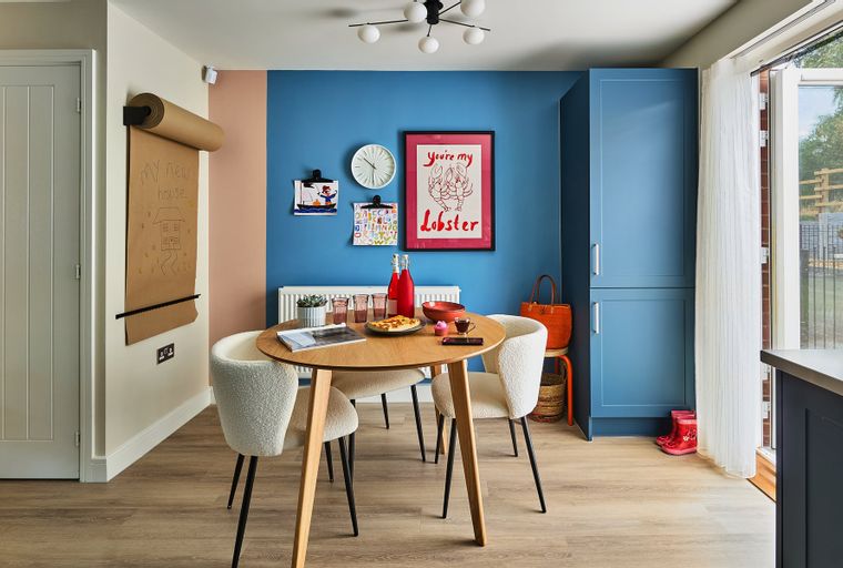A dining area with a round table, chairs, and a blue cabinet.