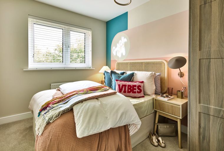 A bedroom with a bed, pillows, a bedside table, and a window.