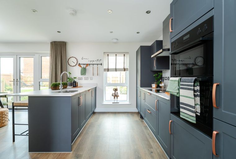 A modern kitchen with dark grey cabinets, a central island, and integrated appliances.