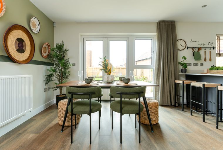 A dining area with a wooden table, green chairs, and a kitchen island with bar stools.