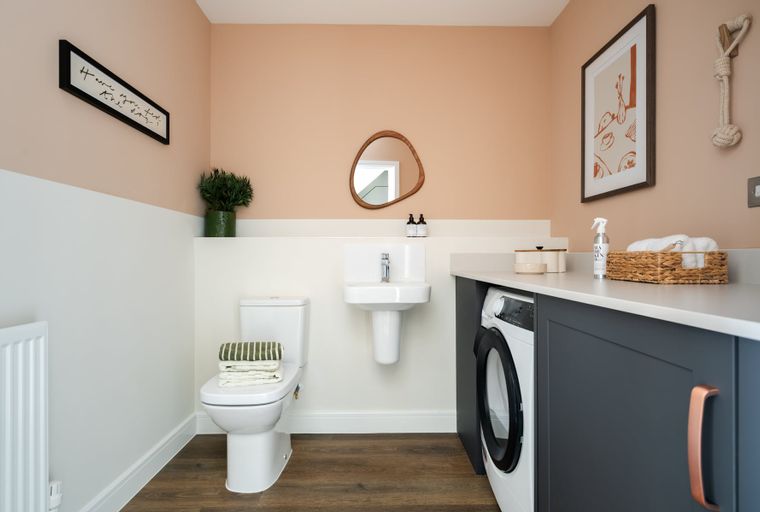 A laundry room with a toilet, sink, and washing machine.