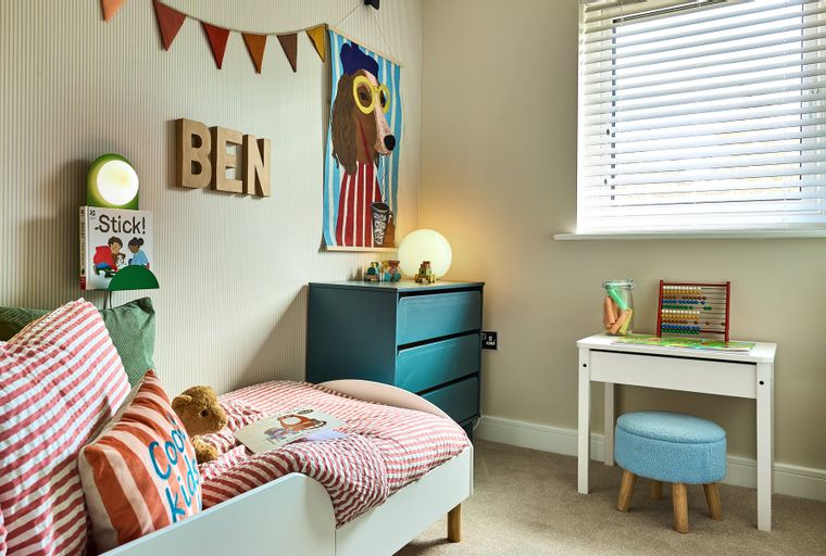 A child's bedroom with a bed, dresser, and desk.