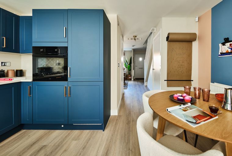 A kitchen and dining area with blue cabinets, a round table, and chairs.