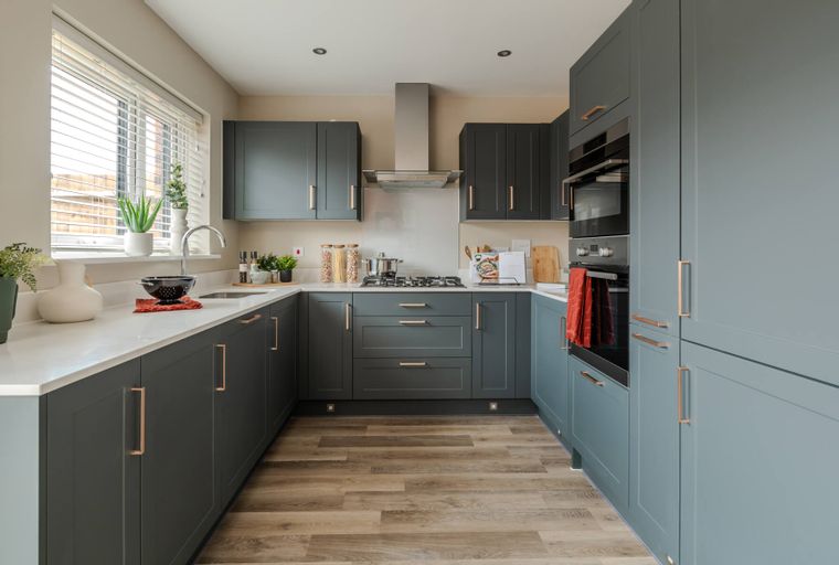 A U-shaped kitchen with dark gray cabinets, white countertops, and stainless steel appliances.