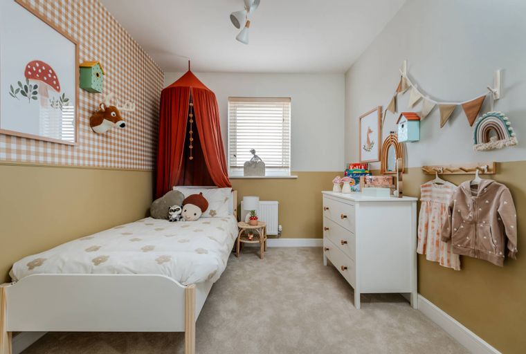 A children's bedroom with a bed, dresser, and decorative wall hangings.