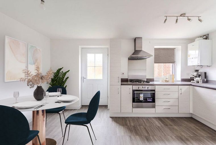 A kitchen and dining area with a table, chairs, cabinets, and a stove.