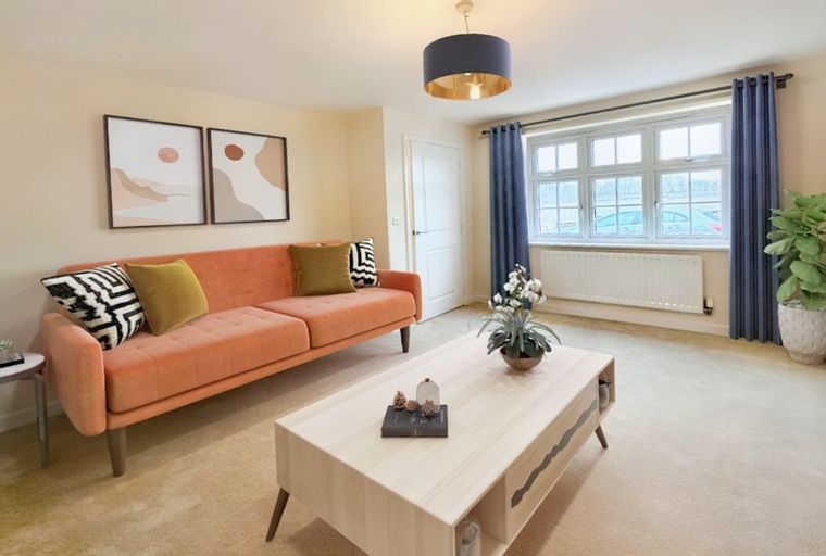 A living room with a coral sofa, coffee table, and a large window.
