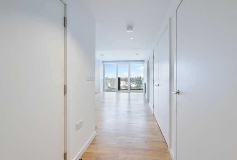 A hallway with white doors and a view of a city skyline through large windows.