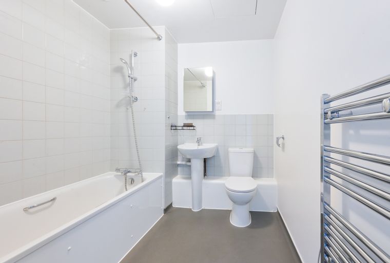 A bathroom with a bathtub, toilet, sink, and towel warmer.