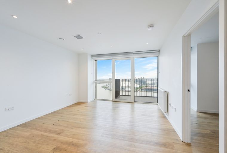 An empty living room with large windows overlooking a city and river.