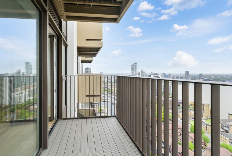 A balcony overlooking a city skyline with a river and boats.