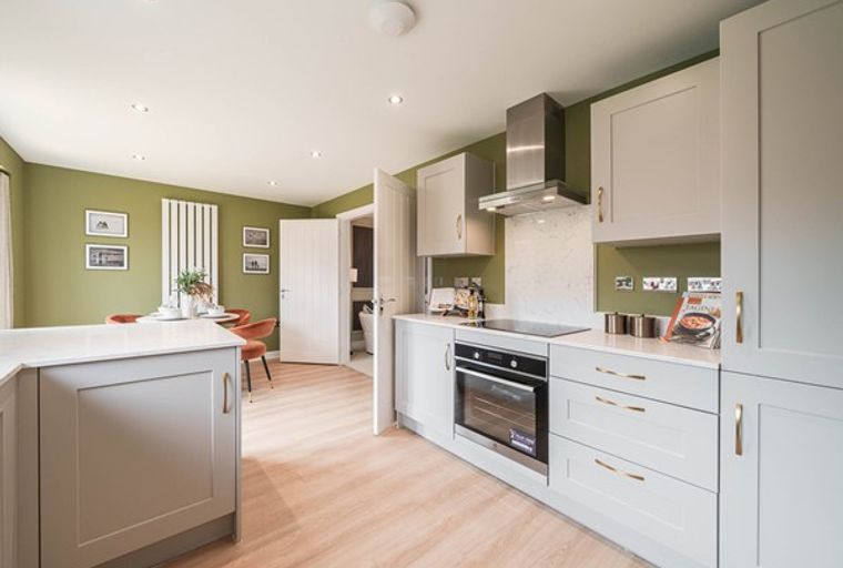 A modern kitchen and dining area with grey cabinets, a built-in oven, and a green accent wall.