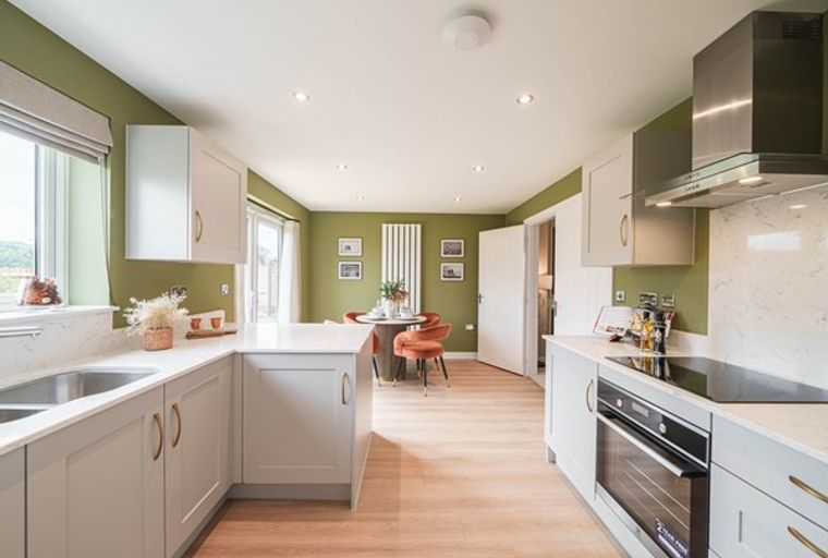 A modern kitchen with grey cabinets, a white countertop, and an oven.
