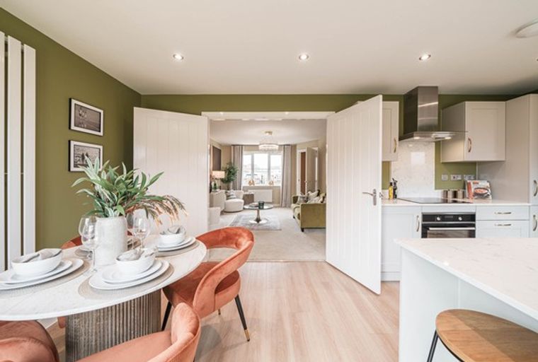 A dining area and kitchen with an open doorway to a living room.
