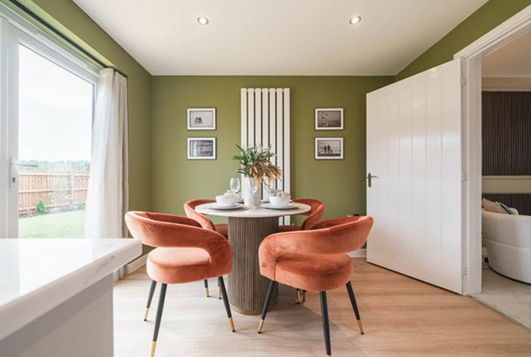 A dining area with a round table, orange chairs, and a sliding glass door.