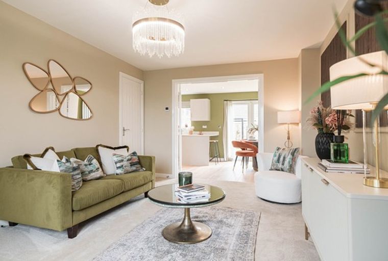 A living room with a green sofa, a coffee table, and a mirrored wall art.