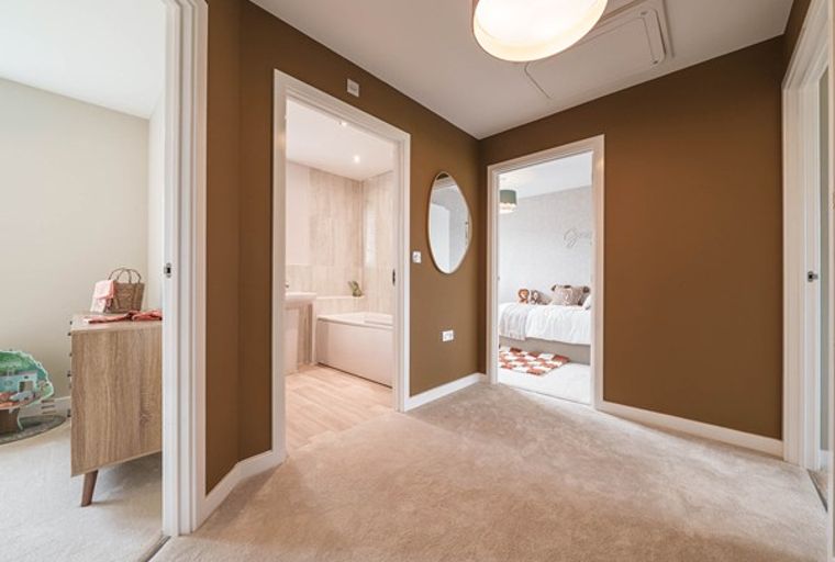 A hallway with two doorways, one leading to a bathroom and the other to a bedroom.