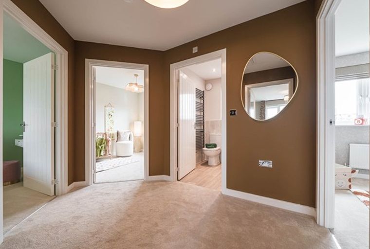 A hallway with multiple doorways leading to different rooms, including a bathroom and a nursery.
