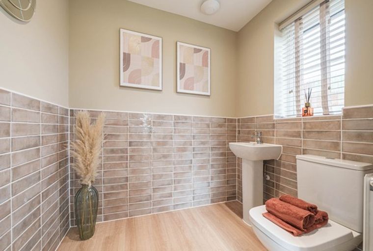 A bathroom with a toilet, sink, and tiled walls.