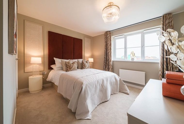 A bedroom with a bed, headboard, bedside tables, lamps, and a window.