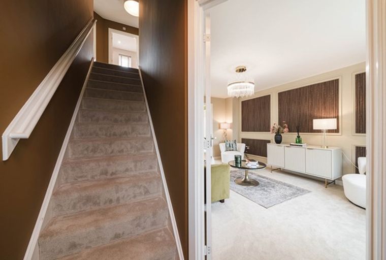 A staircase leading to a living room with a sideboard and seating.