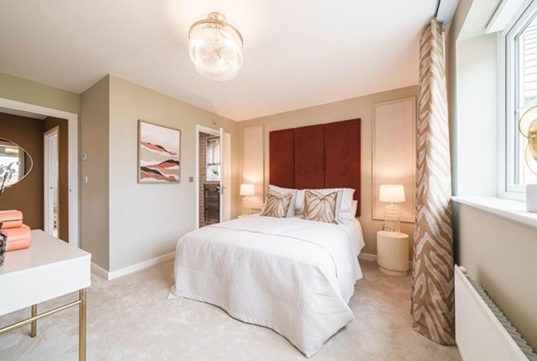 A bedroom with a bed, headboard, bedside tables, and a vanity.
