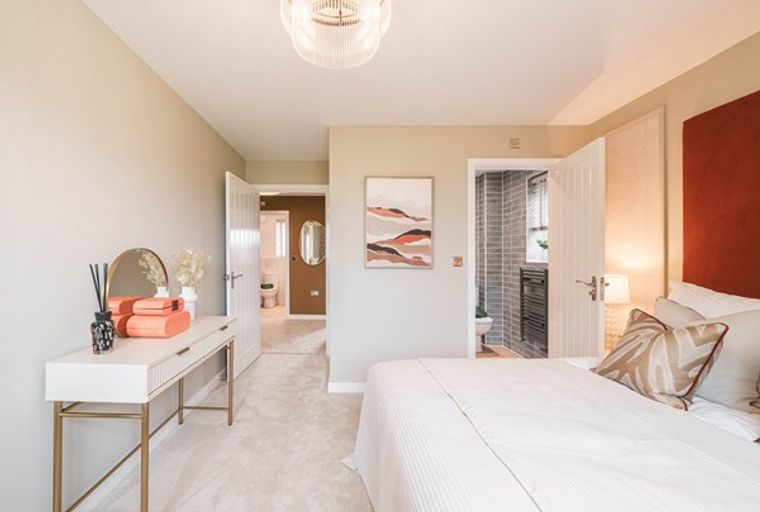 A bedroom with a vanity table, a bed, and a doorway leading to a bathroom.