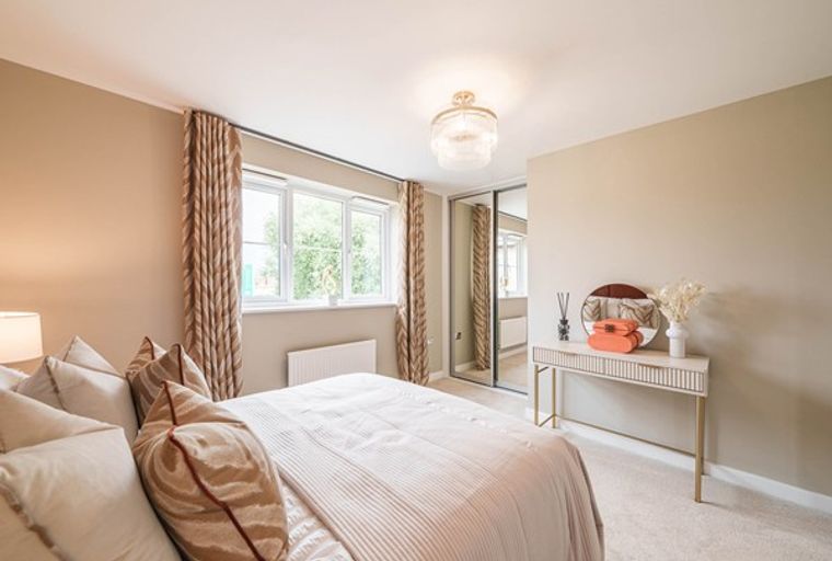 A bedroom with a bed, pillows, curtains, a window, a dresser, and a wardrobe.