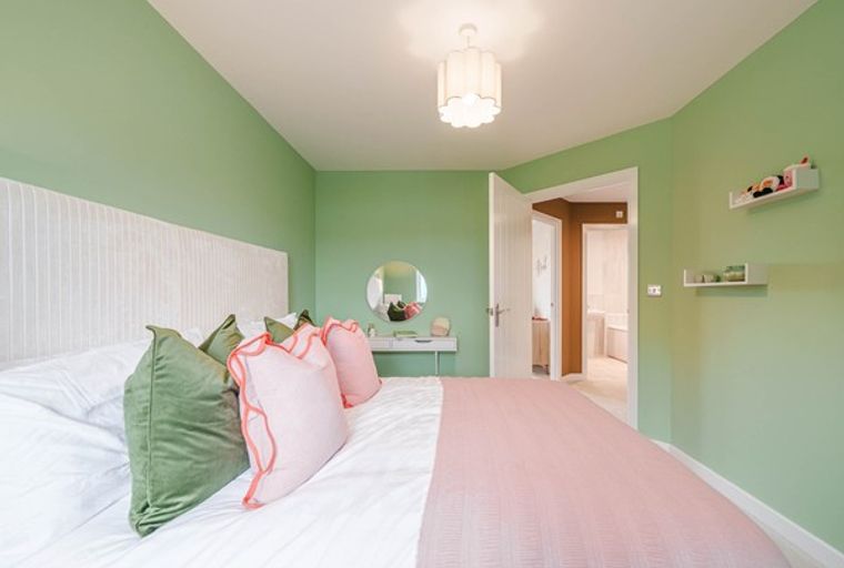 A bedroom with a bed, pillows, a headboard, a vanity, a mirror, and shelves.