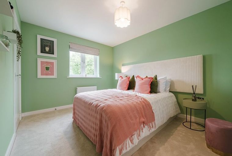 A bedroom with a bed, pillows, a throw blanket, and artwork on the wall.