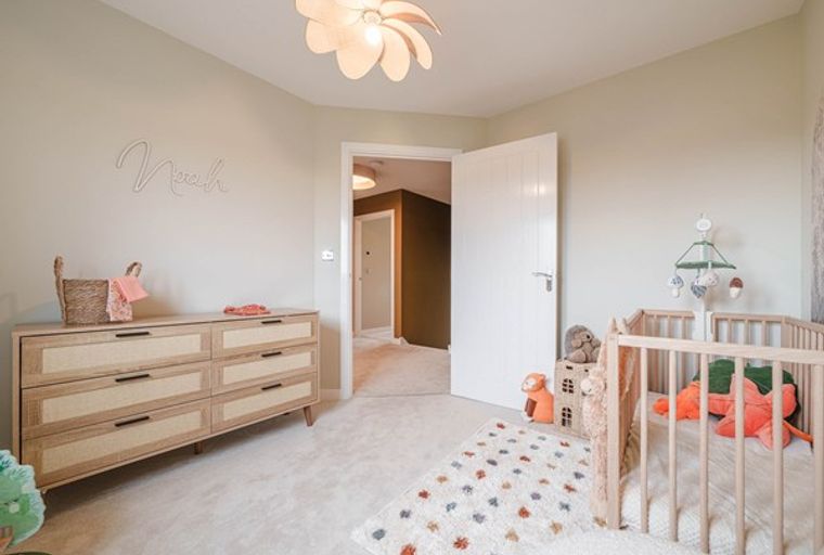 A nursery with a crib, dresser, and a mobile.