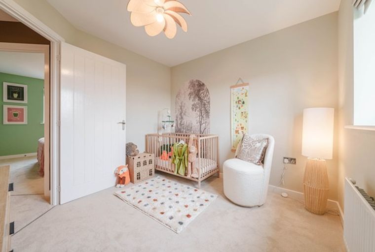 A nursery with a crib, armchair, and a floor lamp.